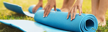 Fundamental Groundwork Awareness Through Movement Program Feldenkrais Method product image of two people on a lawn rolling up Feldenkrais exercise mats.